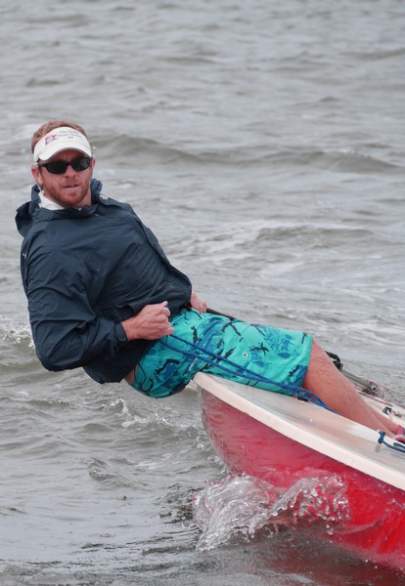 Man sailing while leaning close to the water