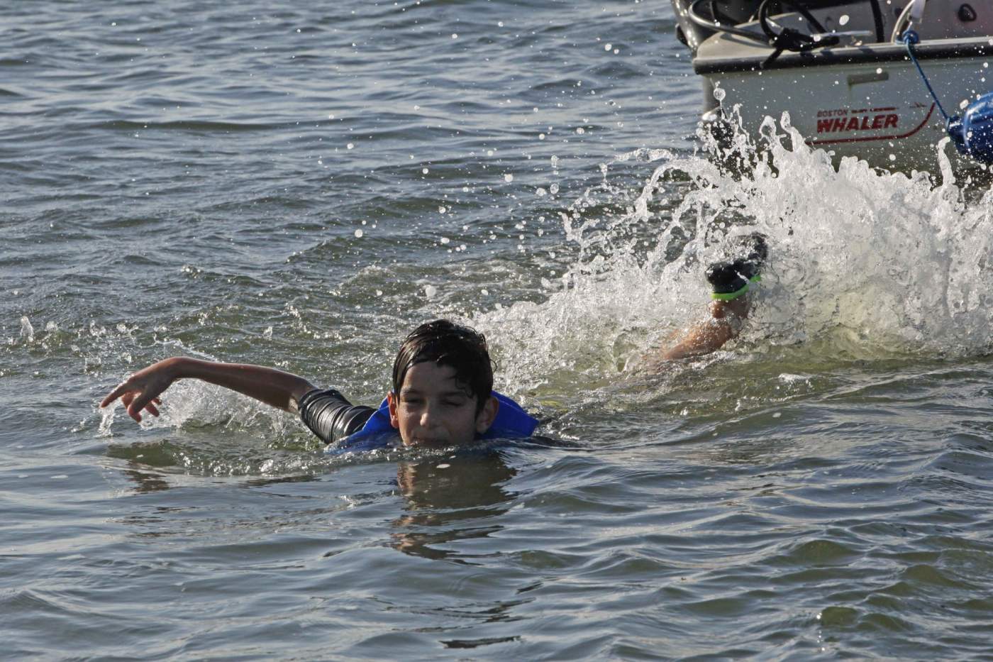 Young boy swimming away from boat