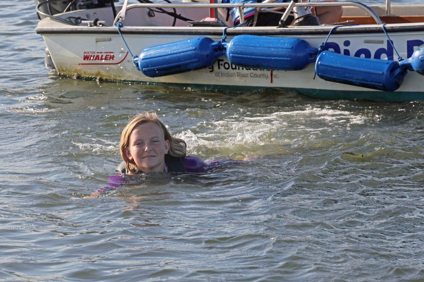 Young girl swimming away from boat