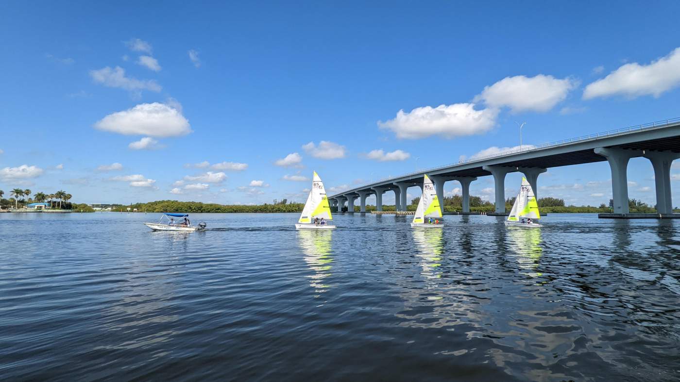 Three sailboats near a bridge