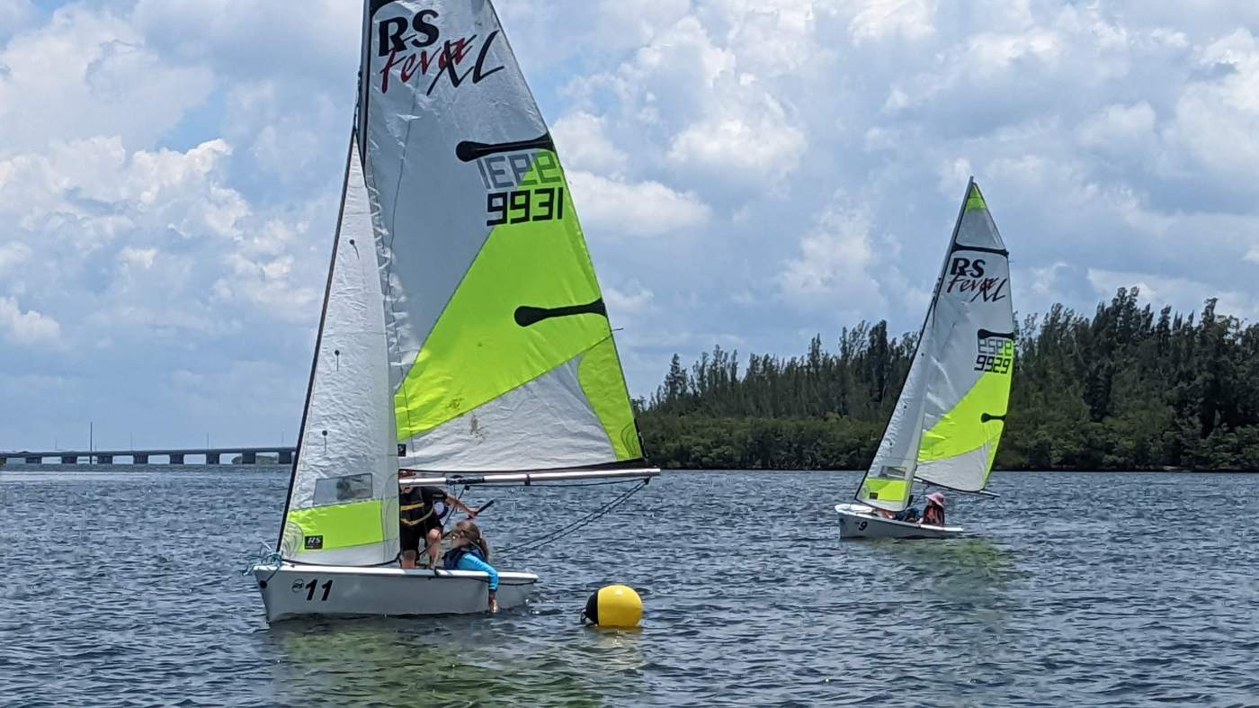 A pair of sailboats passing a buoy