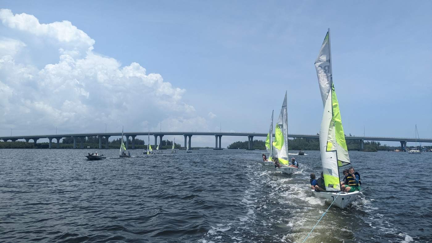 A sailboat being towed followed by other sailboats