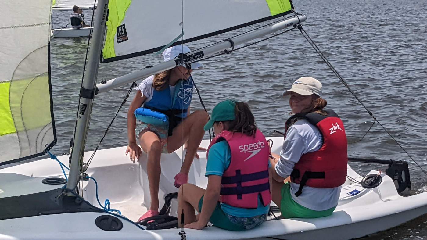 Three girls sailing a boat