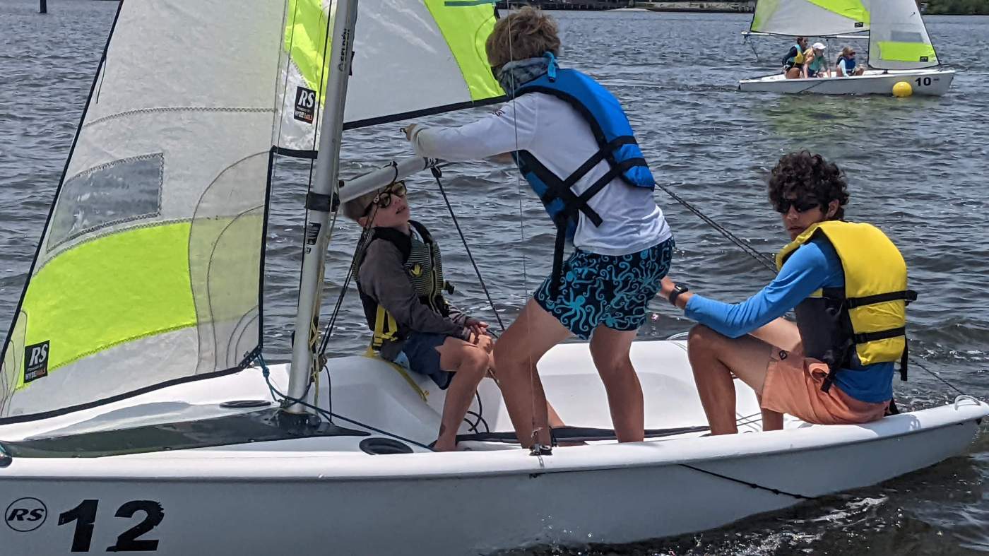 Three boys sailing a boat