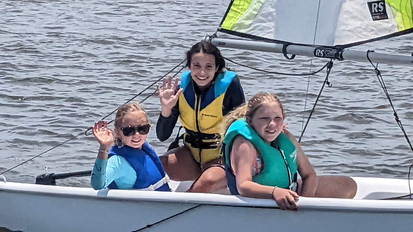 Three girls sailing a boat