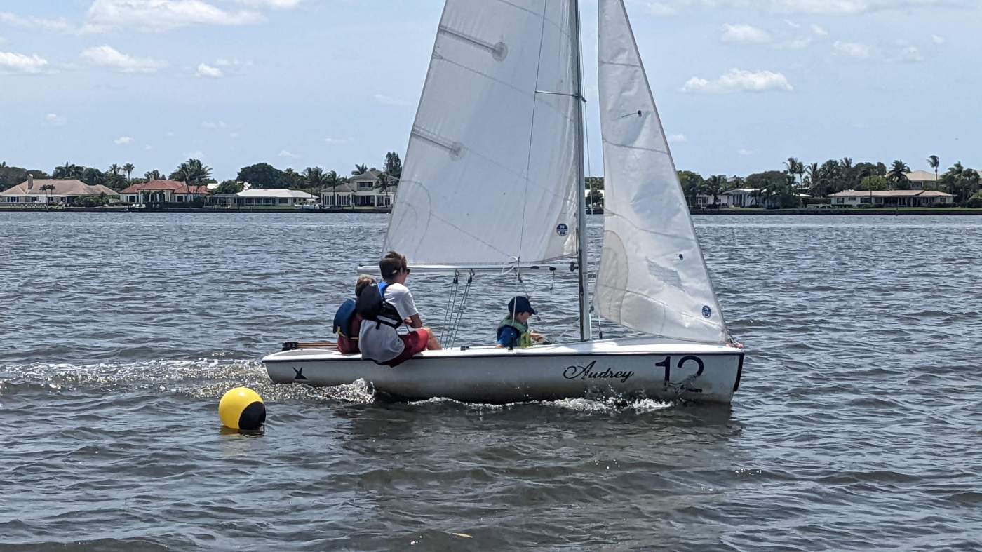 Three boys sailing a boat