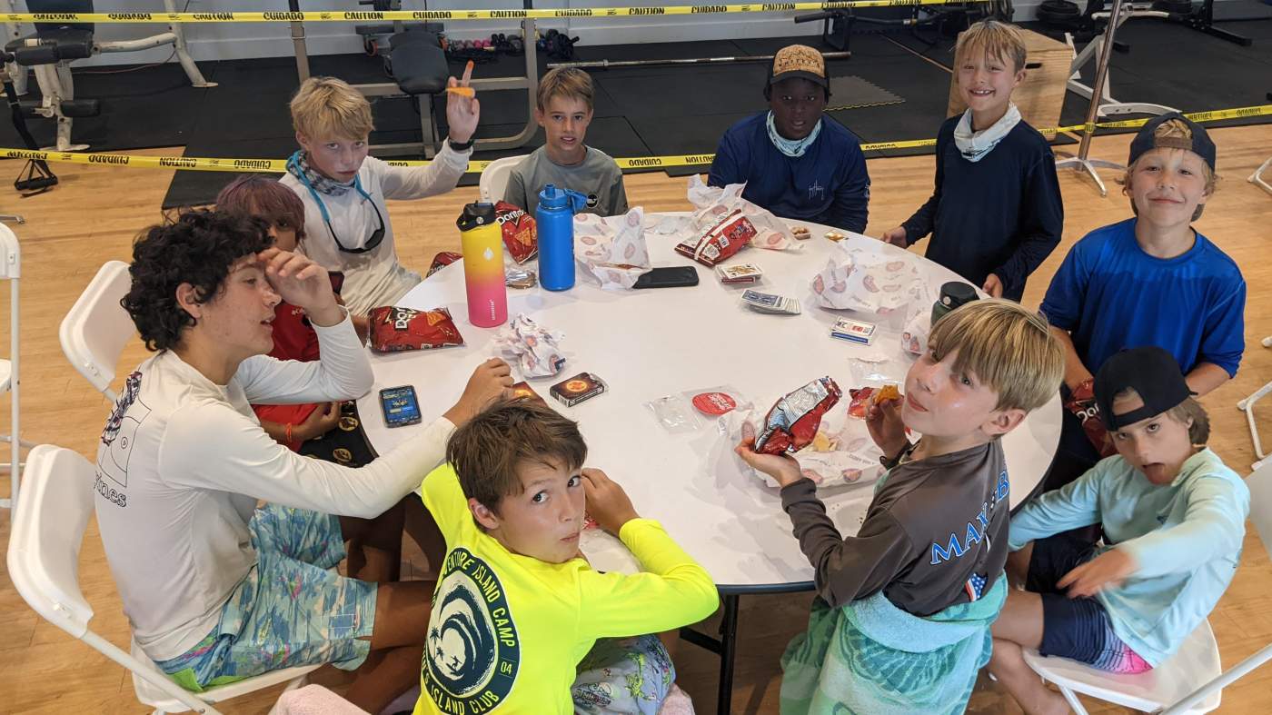 A group of boys seated around a table having snack