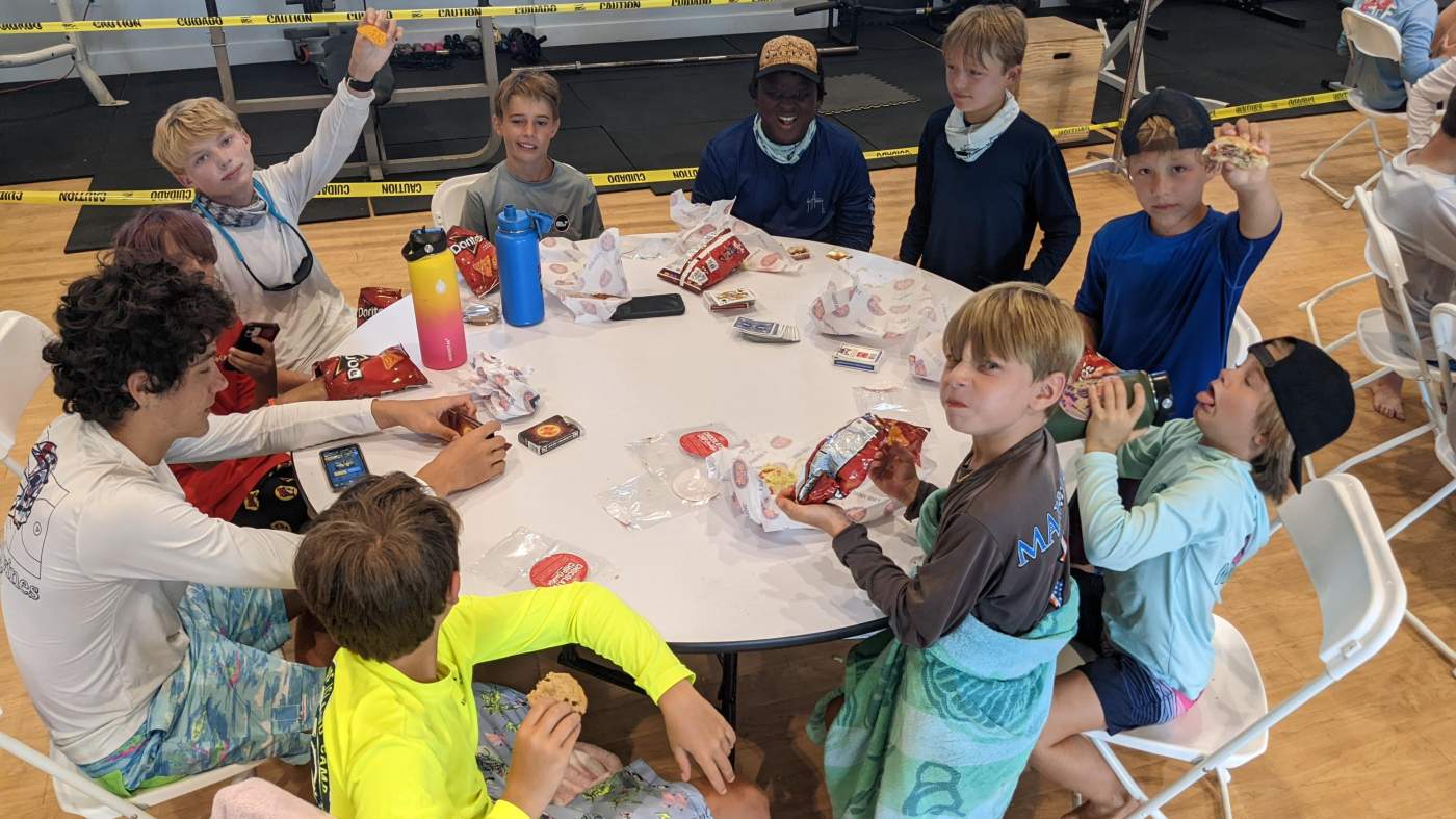 A group of boys seated around a table having snack