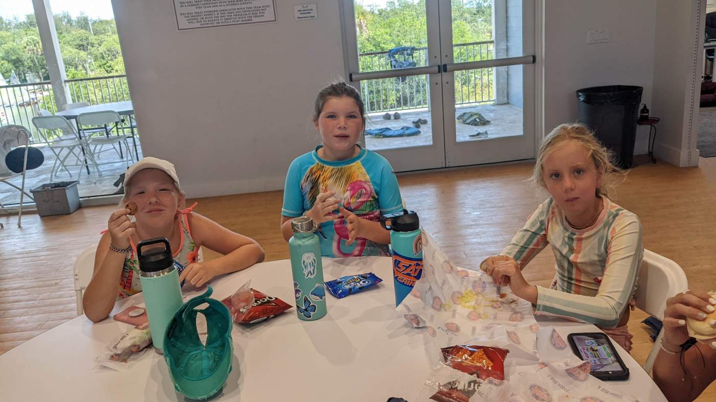 A group of girls seated around a table having snack