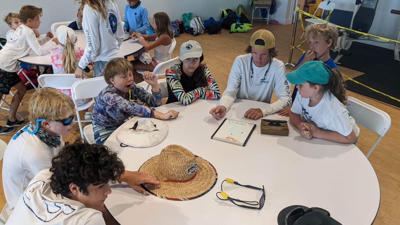 A group of children seated around several tables