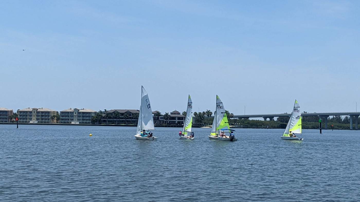 Four sailboats sailing in the lagoon with a bridge in the background