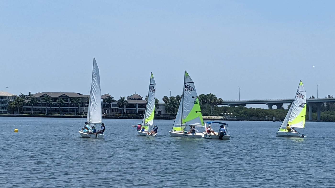 Four sailboats sailing in the lagoon with a bridge in the background