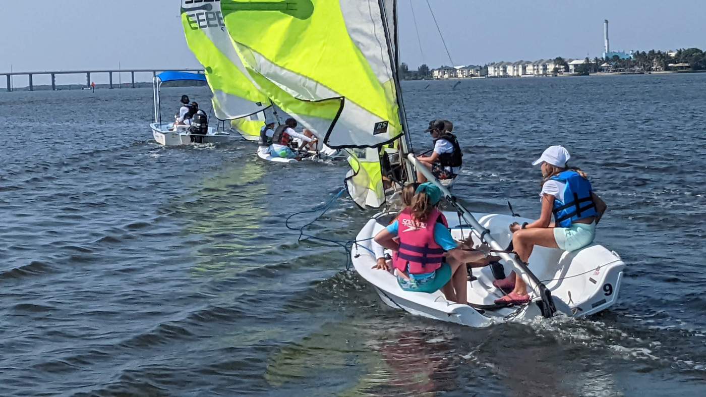 Three sailboats being towed by a powerboat