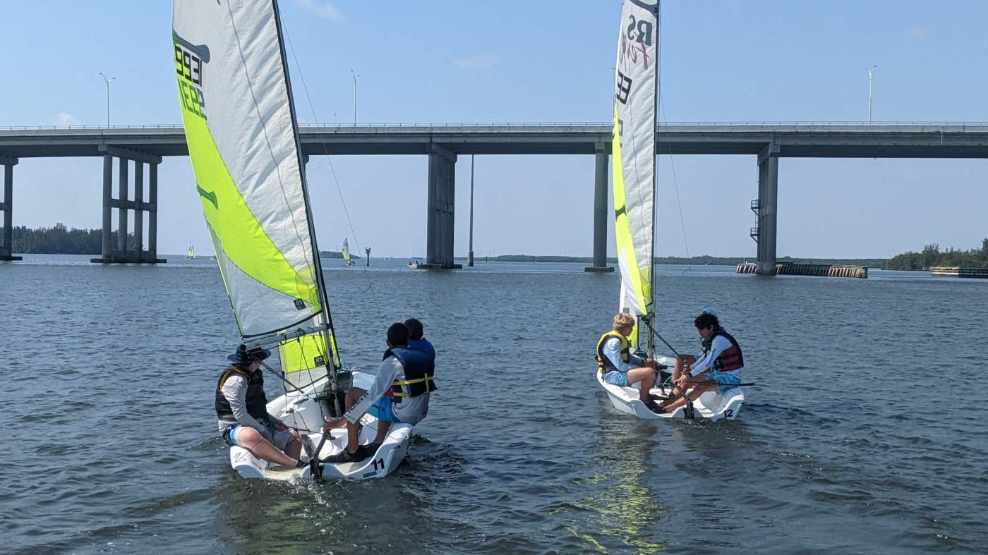 Two sailboats heading towards the bridge