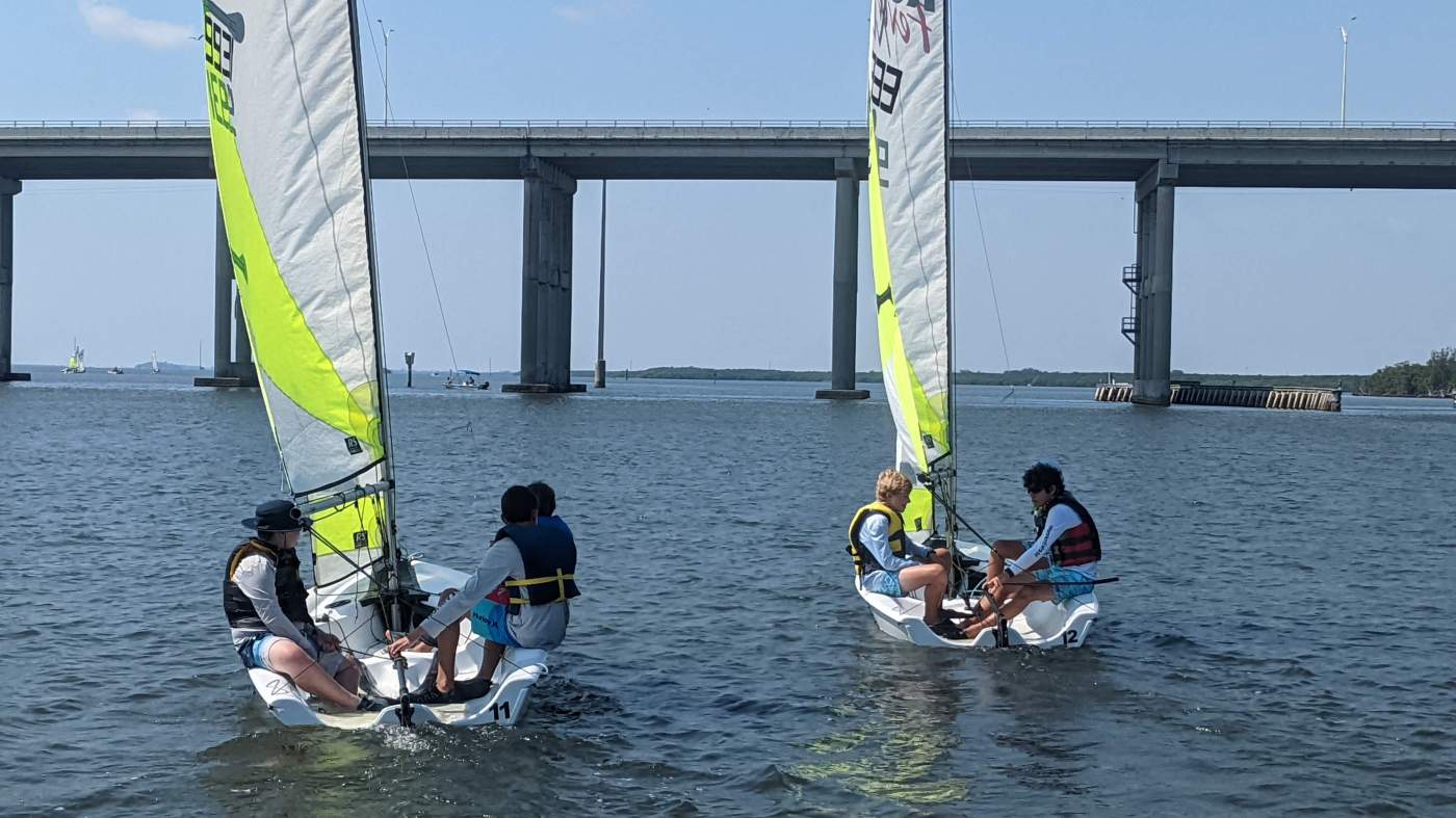 Two sailboats heading towards the bridge