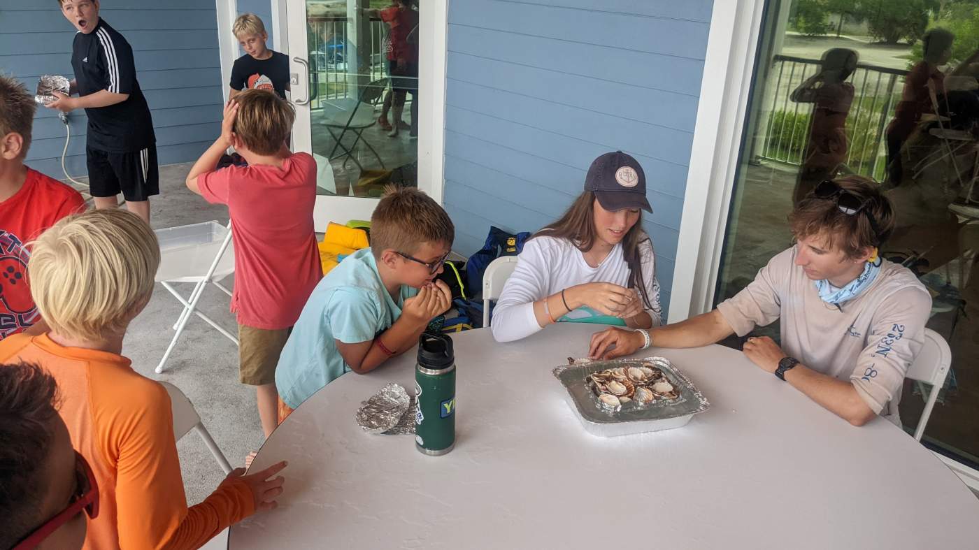 A group of children seated around several tables, having a snack