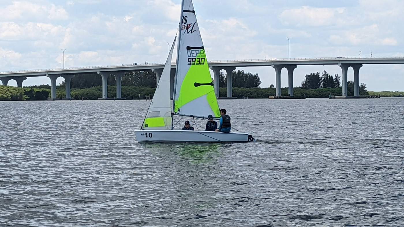 A lone sailboat on the lagoon with a bridge in the background