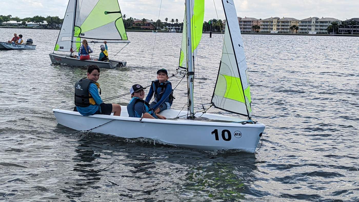 Three boys sailing a boat