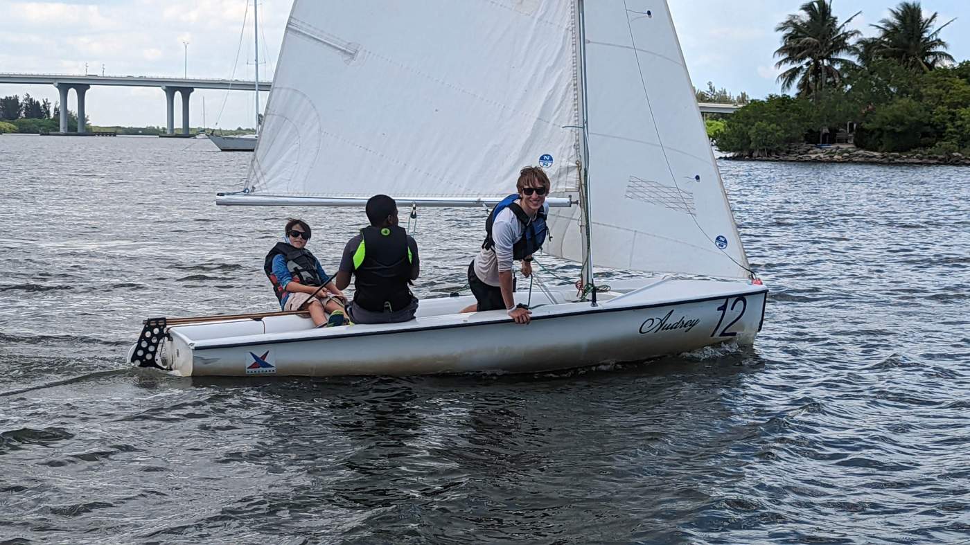 Three boys sailing a boat