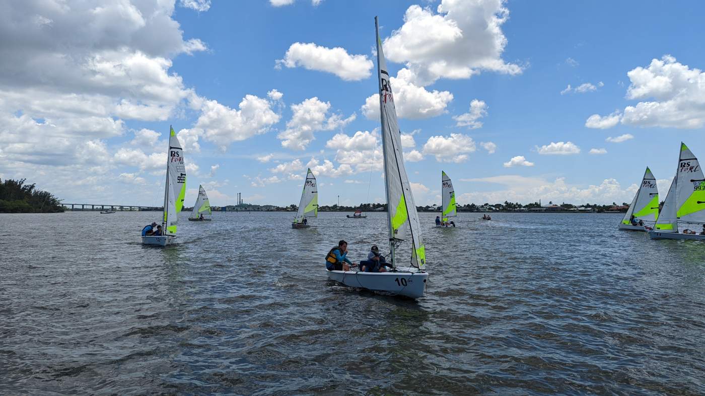 A group of sailboats sailing in the lagoon with a bridge in the background