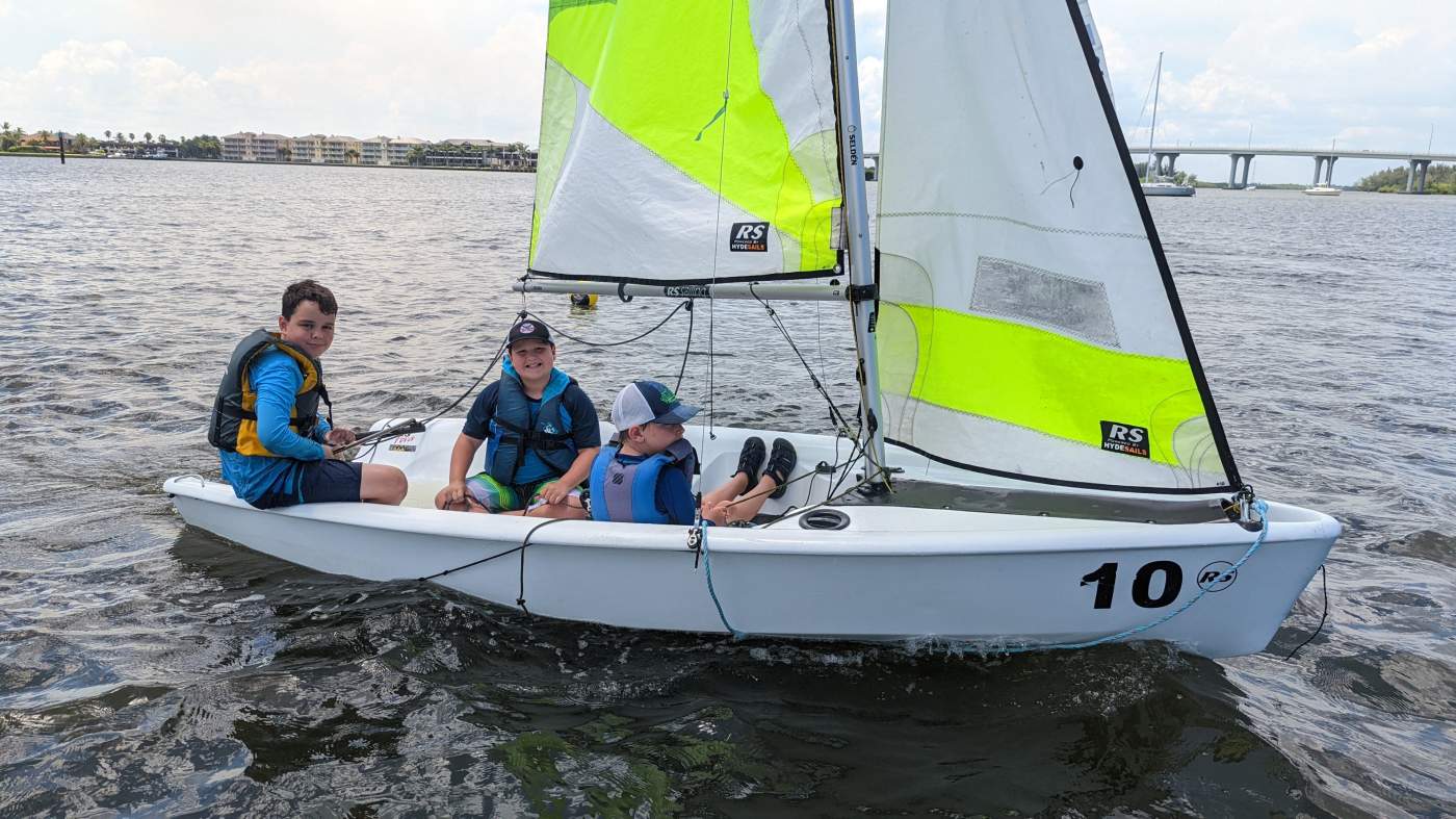 Three boys sailing a boat