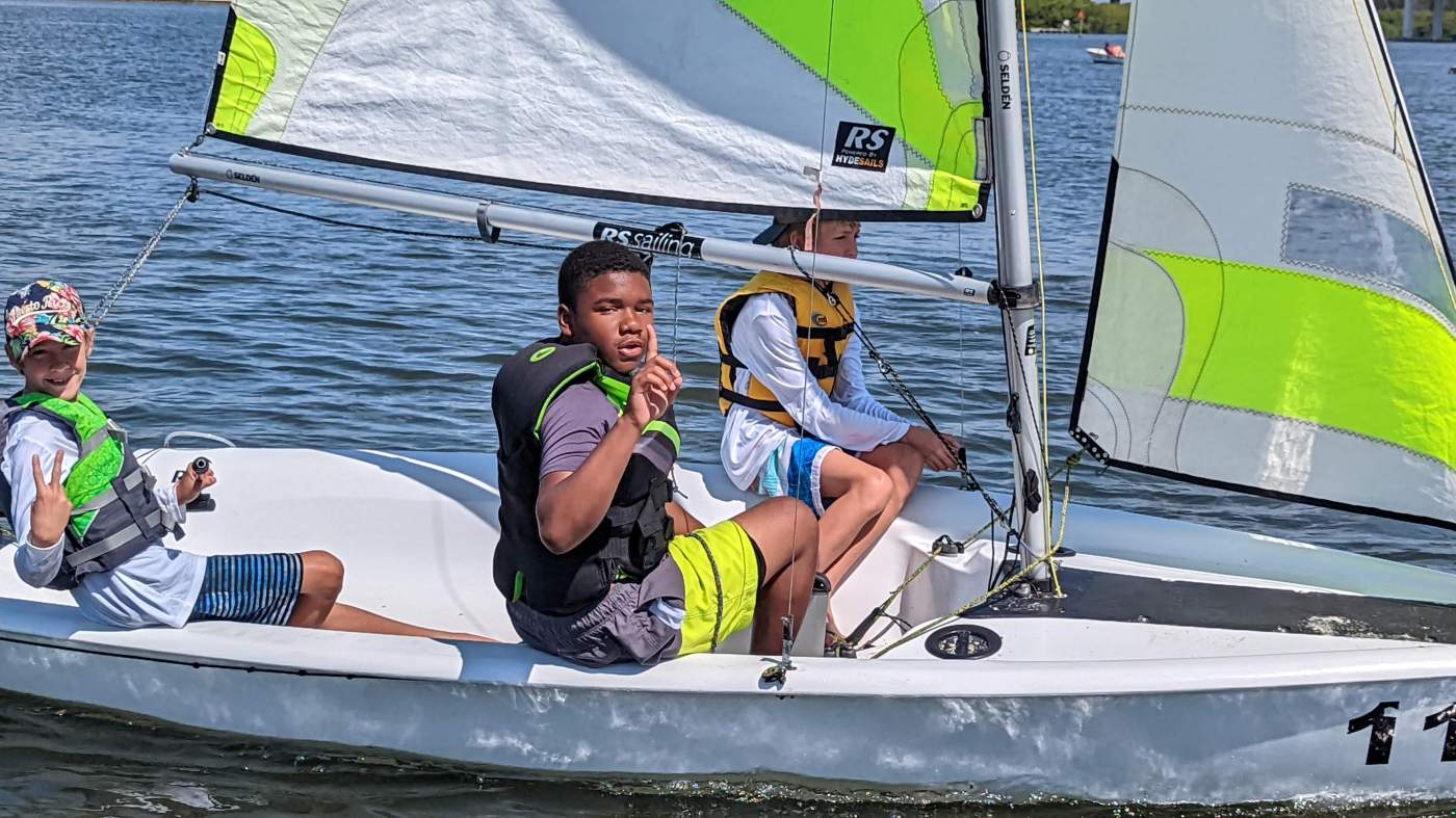 Three boys sailing a boat