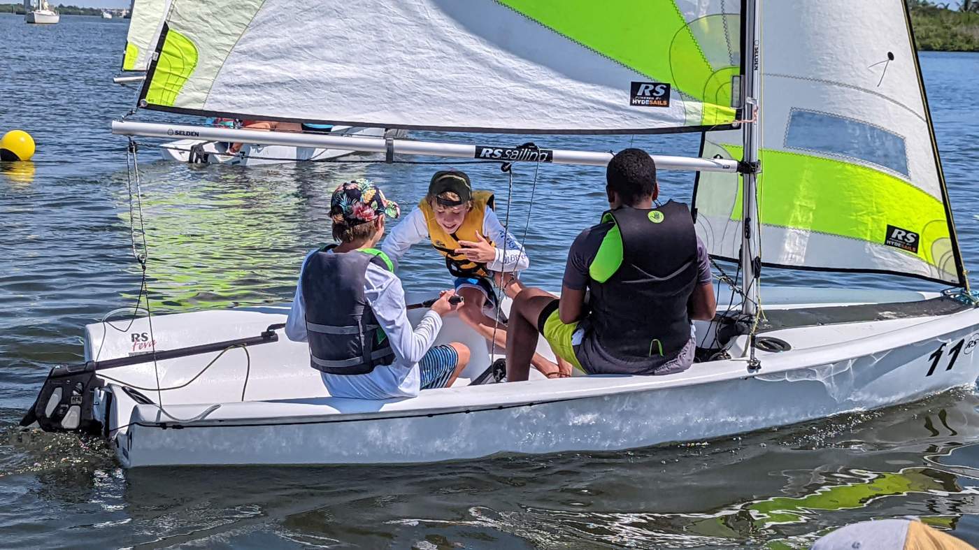 Three boys sailing a boat