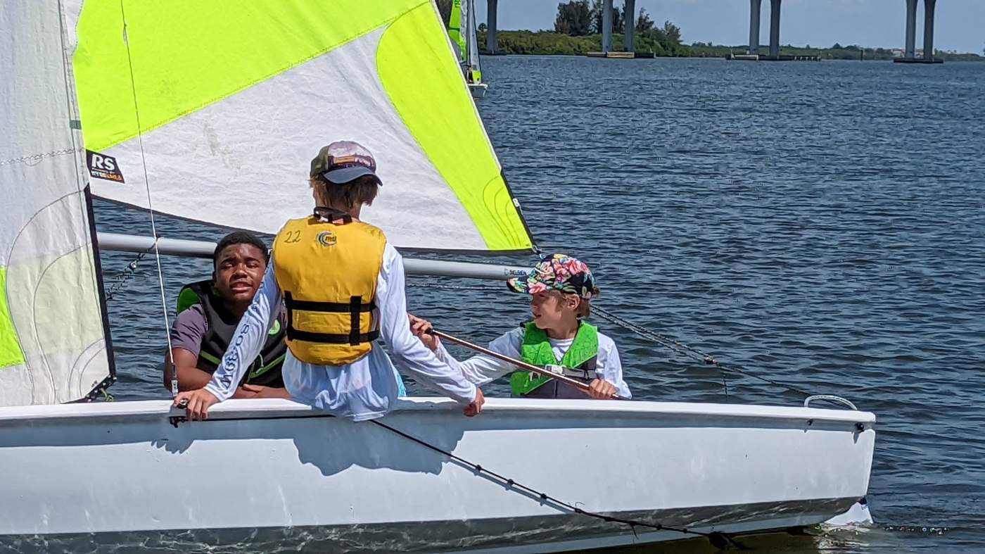 Three boys sailing a boat