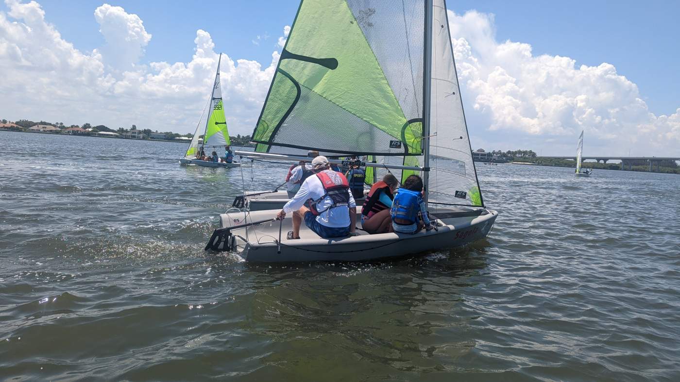 Children sailing a sailboat on the lagoon with a bridge in the background