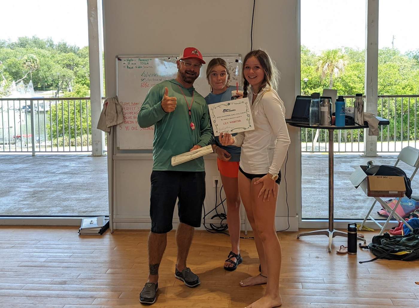 An instructor and several students standing in front of a whiteboard. One is receiving a certificate