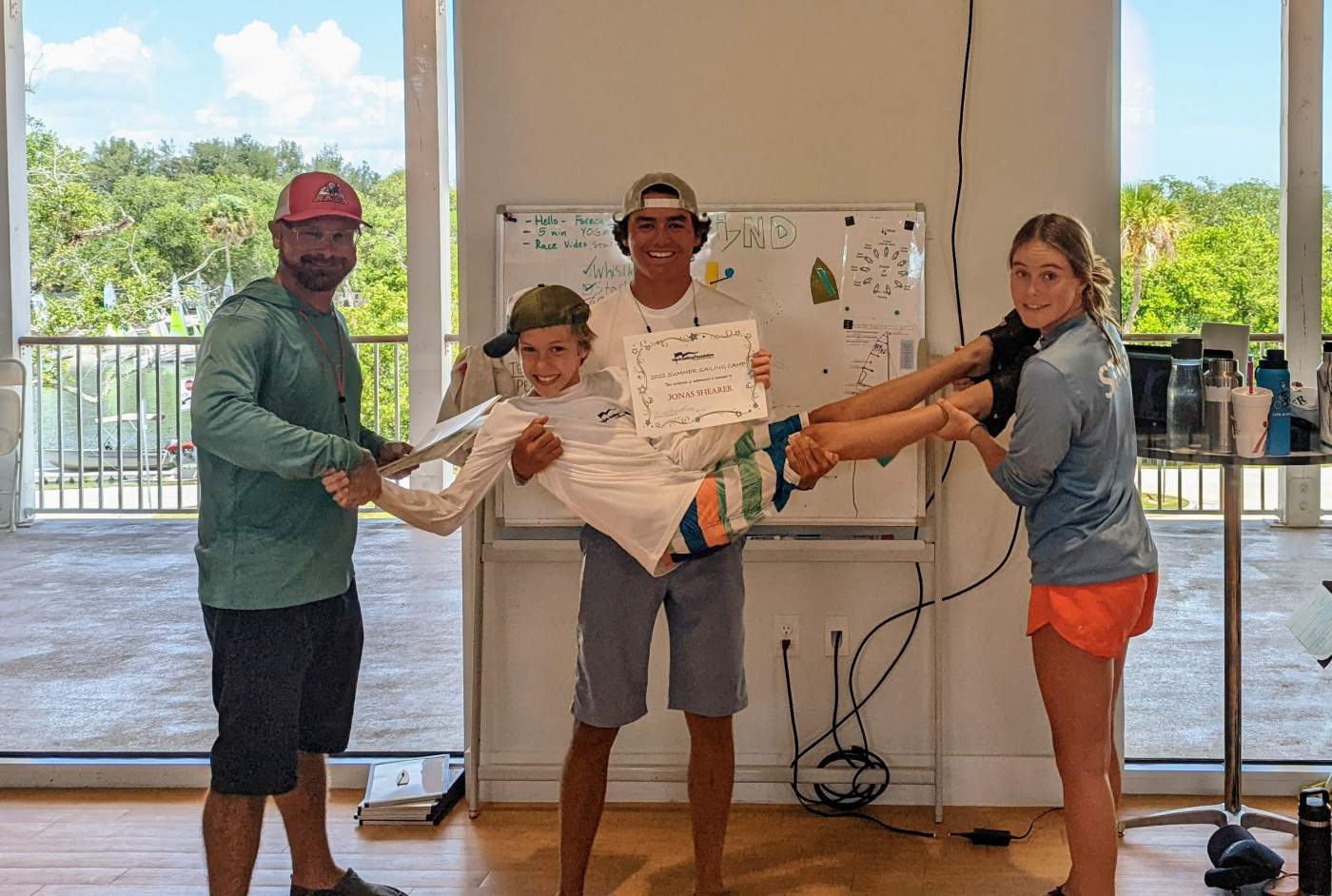 An instructor and several students standing in front of a whiteboard. One is receiving a certificate