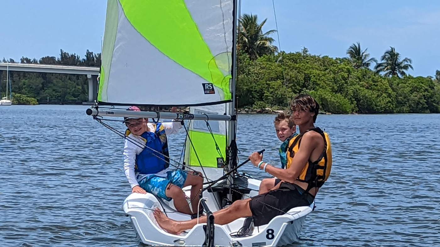 Three boys sailing a boat