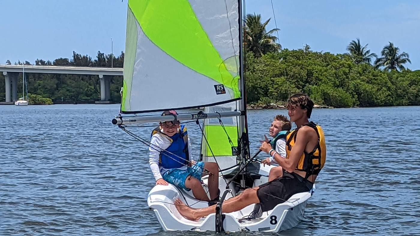 Three boys sailing a boat