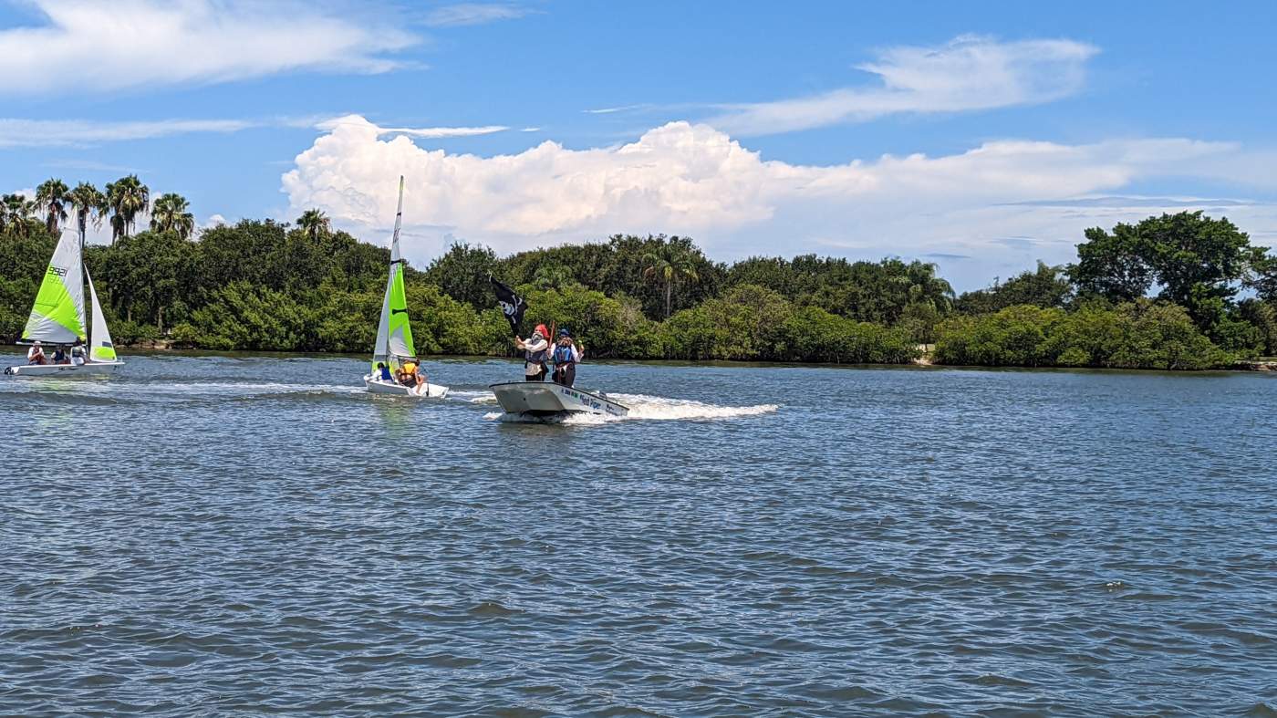 Powerboat flying a pirate flag with two sailboats in the background