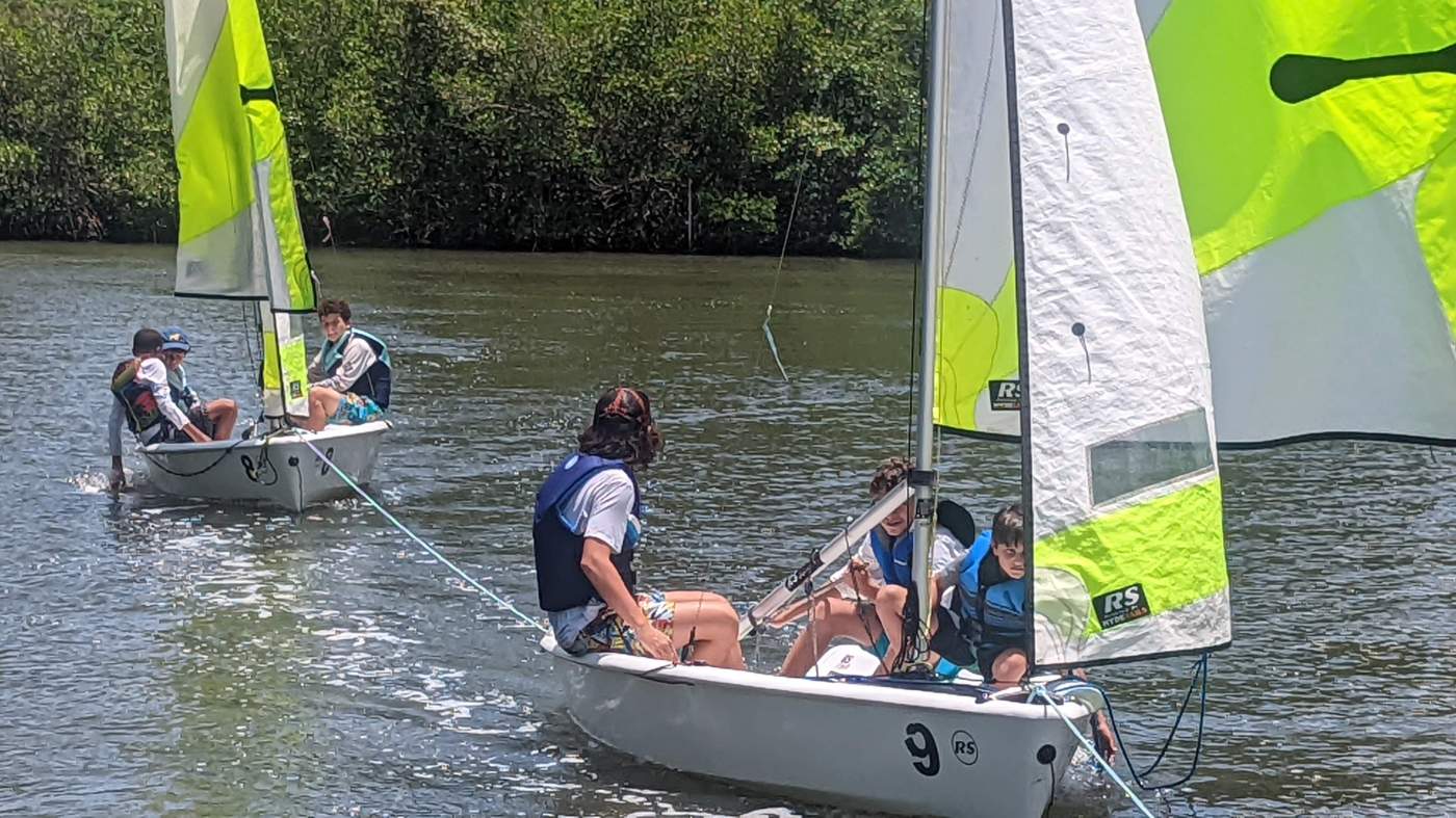 Three sailboats being towed by a powerboat