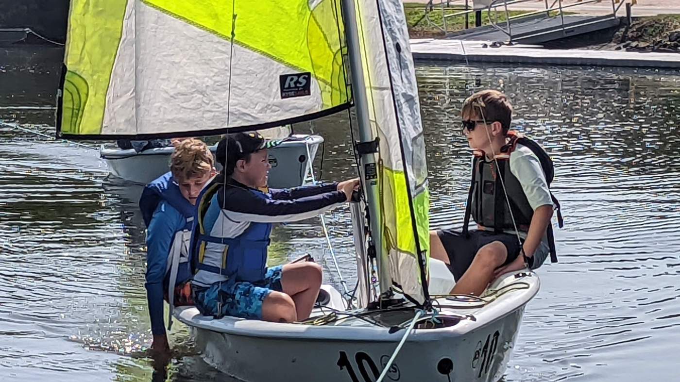 Three boys sailing a boat