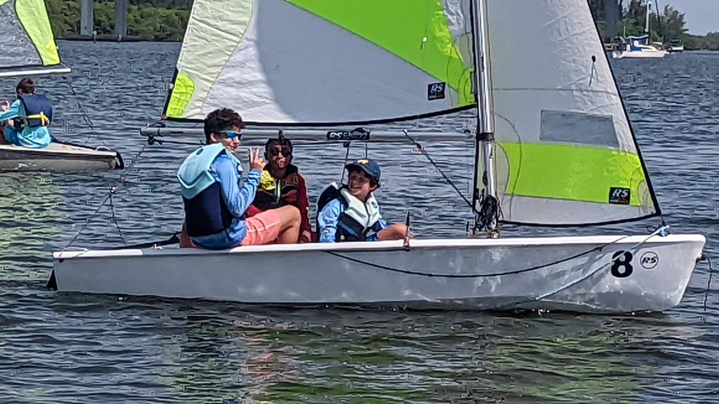 Three boys sailing a boat