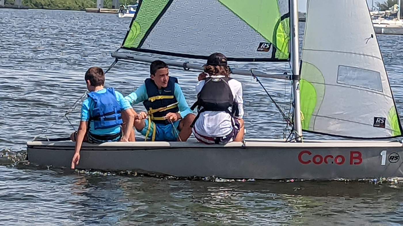 Three boys sailing a boat