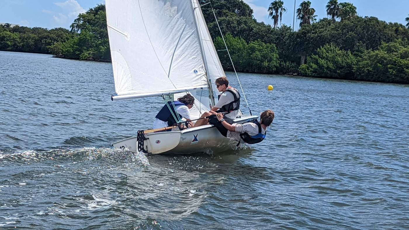 Three boys sailing a boat