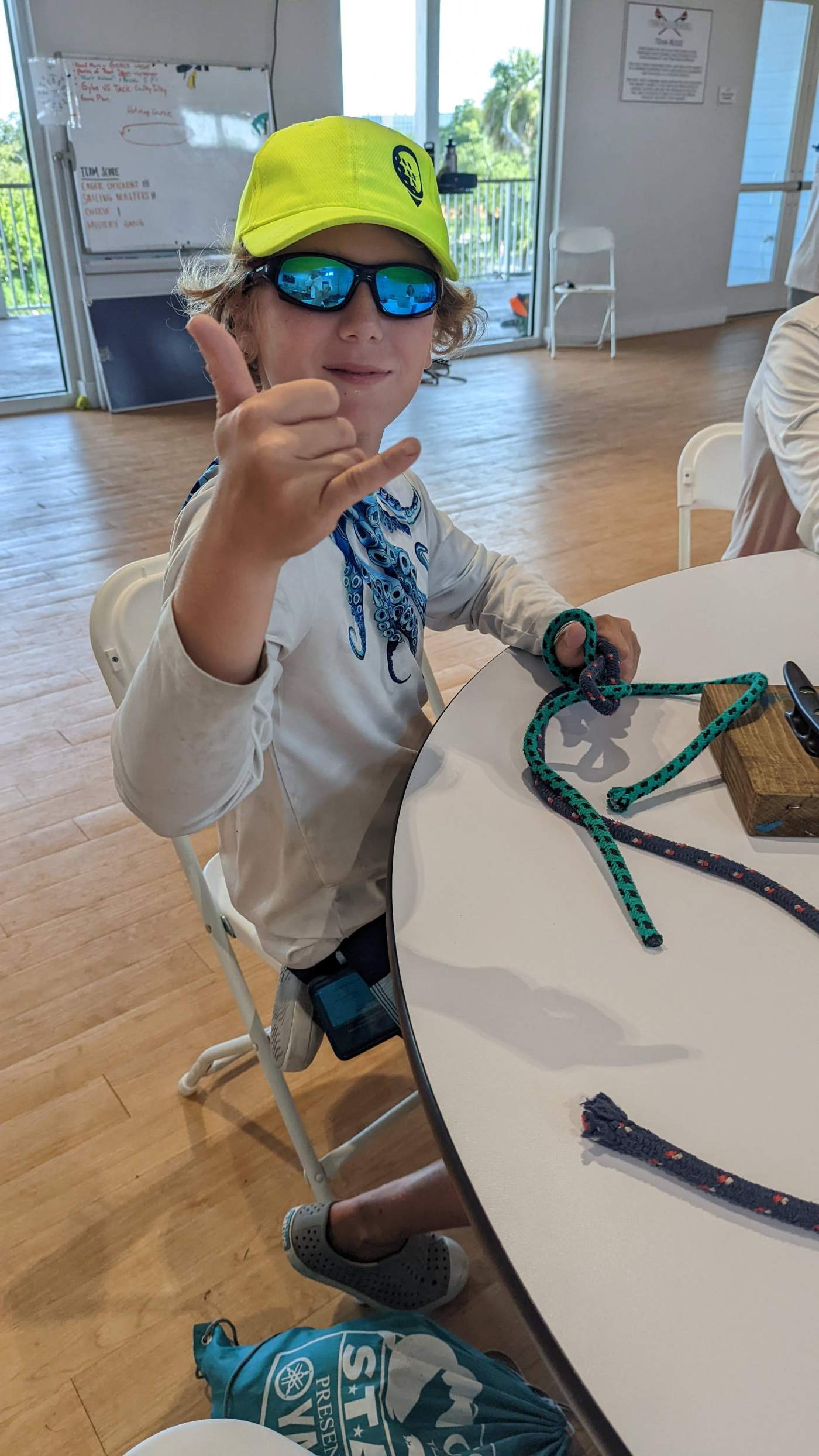 A young man seated at a table giving a thumb's up