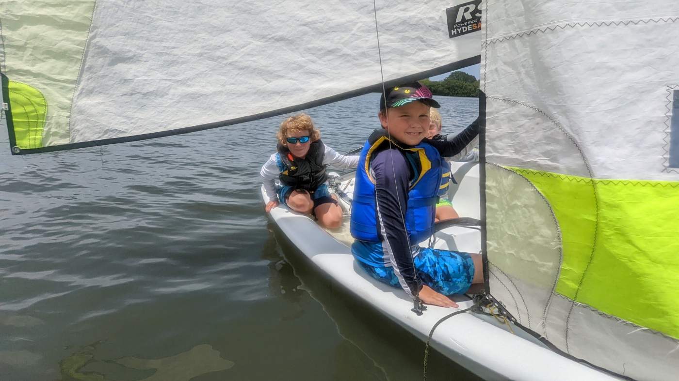 Three boys sailing a boat