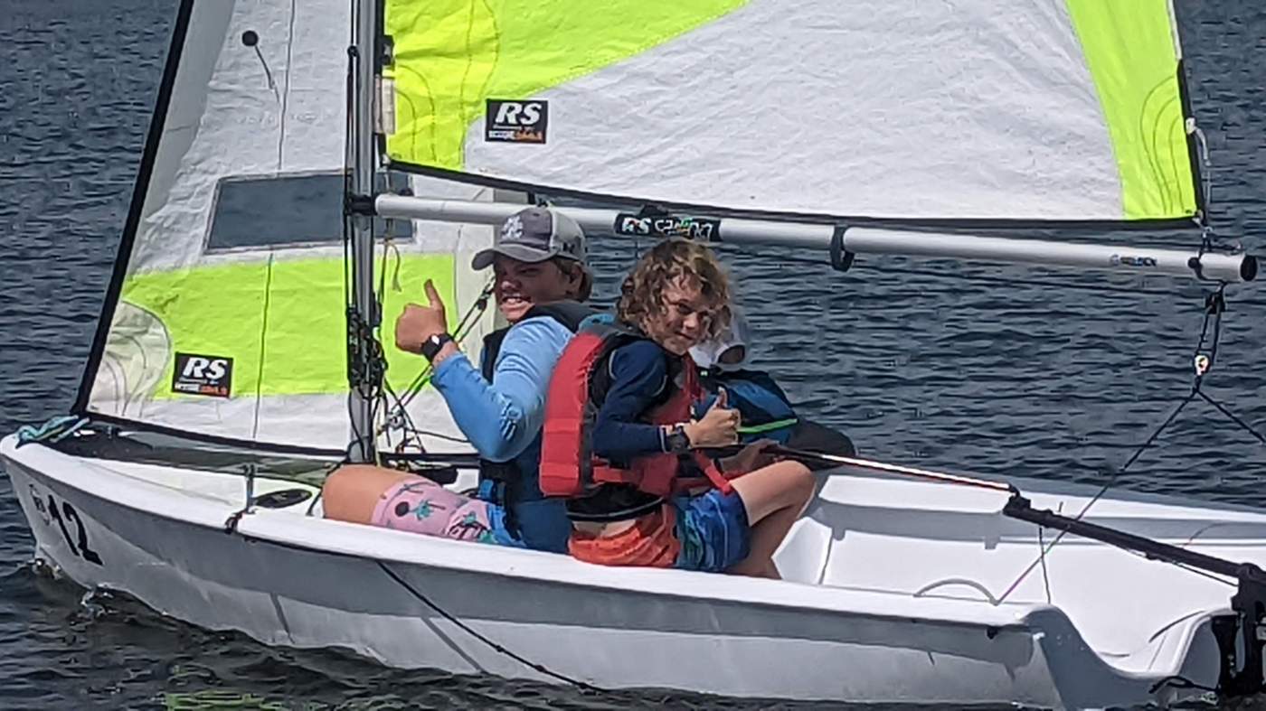 Three boys sailing a boat