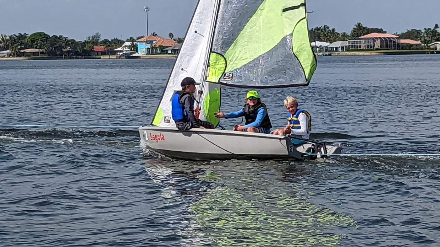 Three boys sailing a boat