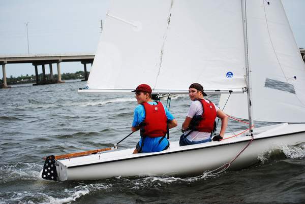 Two young adults sailing with one facing the camera