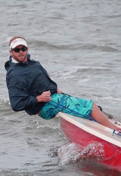 Man sailing while leaning close to the water